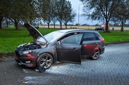 Automobilist blust eigen auto met poederblusser van tankstation