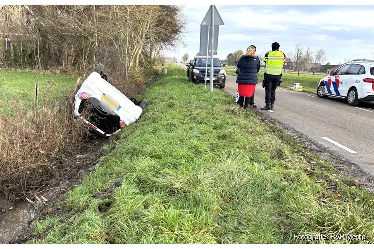 Auto met twee inzittenden op zijn kop op de Rikkert in Andijk