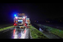 Auto ondersteboven in sloot op spiegelgladde weg, bestuurster met spoed naar ziekenhuis
