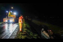 Auto ondersteboven in sloot op spiegelgladde weg, bestuurster met spoed naar ziekenhuis